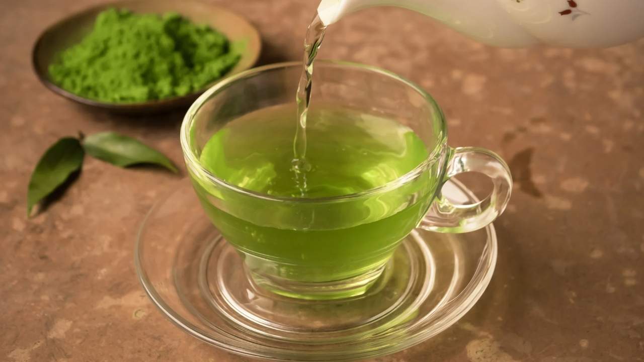 green tea pouring from teapot into glass