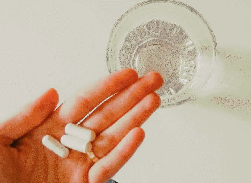 a hand holding three magnesium capsules