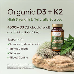 A bottle of Time Health Organic D3 + K2 supplement displayed on a natural wood block with green leaves, set against a pale sage green background with product details and benefits listed on the left.