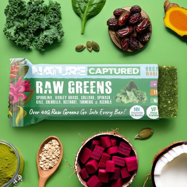 Nature captured raw greens bar on a green background surrounded by organic ingredients: beetroot, gluten-free oats, coconut, spirulina, chlorella, spinach, kale, dates and turmeric